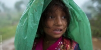 A girl sheltering from monsoon rains in Dhading District, Nepal, in a community where many were still living in temporary shelters after the 2015 earthquakes