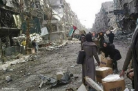 Women with United Nations Relief and Works Agency (UNRWA) aid packages in the besieged Palestinian refugee camp of Yarmouk in Damascus (photo taken on a mobile phone)