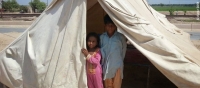Children look out from a temporary tent home after flooding caused by heavy rains in September 2014 affected more than 2 million people. Photo from CARE partner organisation Awaz. 