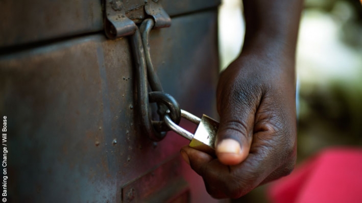 Unlocking the potential of savings groups: A member of the Yesu Amala VSLA group locks the group's shared safe during a meeting of the group's members in Busia District, Eastern Uganda