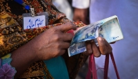 A female road maintenance worker in Pakistan counting her salary during a cash distribution at a mobile service vehicle of Tameer Bank