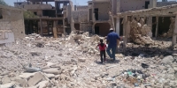 A man and boy carrying emergency shelter materials across bombed out rubble in southern Syria (2016)