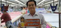 A garment factory manager holds a sign supporting CARE Cambodia&rsquo;s campaign against sexual harassment in the workplace