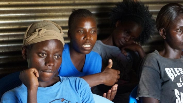 Milca (background, centre) makes a point during a meeting of her VSLA group